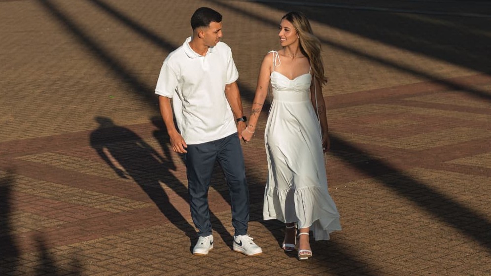 Alysson e Eduarda caminhando de mãos dadas ao fim de tarde